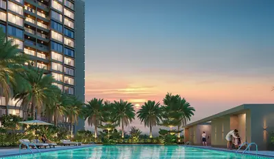 Palm-lined podium swimming pool beside a residential tower at dusk
